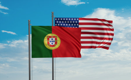 USA and Portugal flag waving together in the wind on blue sky, two country cooperation conceptの写真素材
