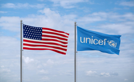 UNICEF and USA flags waving together in the wind on blue cloudy sky, relationship conceptのeditorial素材
