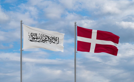 Denmark and Afghanistan flags waving together on blue cloudy sky, two country relationship conceptの写真素材