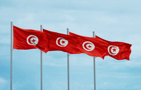 Tunisia four flags in row waving together on blue cloudy sky, multiple flags in lineの写真素材