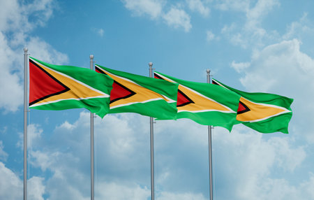 Guyana four flags in row waving together on blue cloudy sky