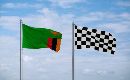 Checkered racing and Zambia flags waving together on blue cloudy sky, two country relationship conceptの写真素材