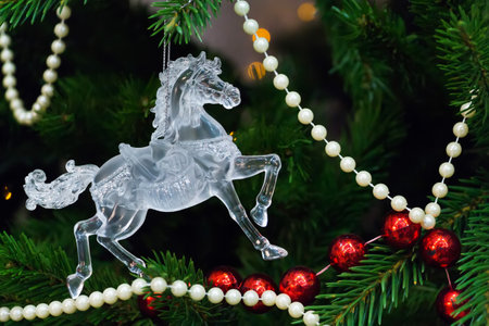 Toy horse on Christmas tree with lights and red and white beadsの写真素材