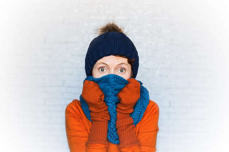 Portrait of open-eyed woman wearing knitted clothes covers her face with a scarf.の写真素材