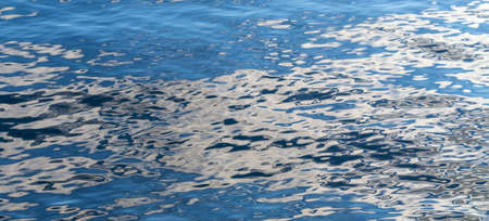 Blue lake water with flecks of sunlight on the surface.