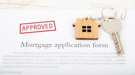 Approved mortgage loan agreement application with a house shaped keyringの写真素材