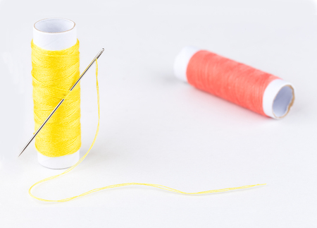 Yellow threads and metal needle on white background  with cope spaceの写真素材