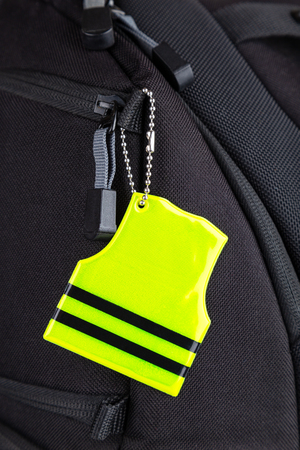 Yellow pedestrain safety reflector on a black backpack, closeup view. Concept of safetyの写真素材
