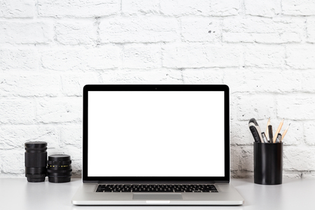 Working place. Laptop with empty screen on grey table. Mockup with copy space on brick wall backgroundの写真素材