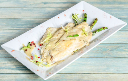Plate of seabass fillet with grilled asparagus on wooden table