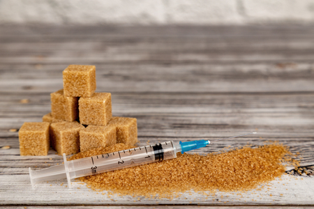 Addiction to sugar concept. Cubes of brown sugar and medical syringeの写真素材