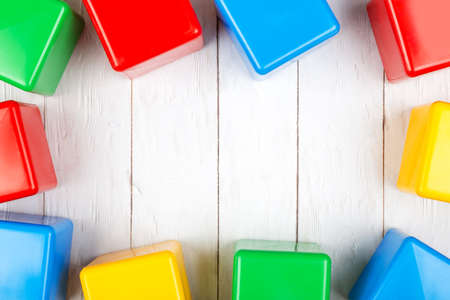 Flat lay with colorful toy cubes on white wooden background. Copy spaceの写真素材