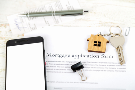 Mockup with smartphone screen and approved mortgage loan agreement application with house shaped keyringの写真素材