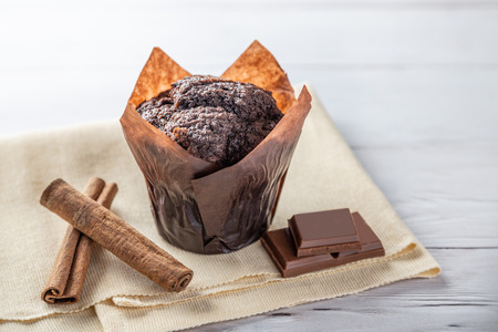 Chocolate muffin cake with pieces of chocolate and cinnamon  on wooden tableの写真素材