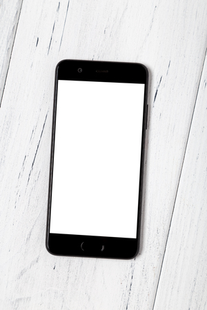 Smartphone with empty screen on white wooden background. Mockup.の写真素材