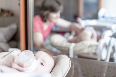 Beautiful young mother feeding her baby from bottle.の写真素材