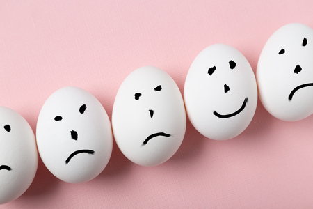 Concept of being unique. Hapyy smile on an egg among sad smilesの写真素材