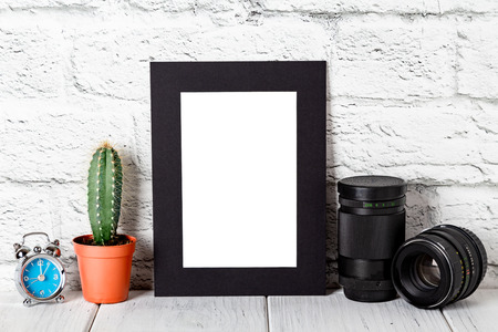 Black cardboard photo frame on white table against brick wall. Mockup against brick wall. Mockup.の写真素材