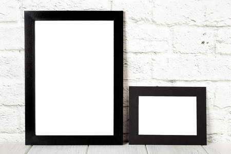 Two black photo frames on wooden table. Mockup with copy space.