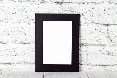 Vertical black photo frame on wooden table. Mockup with copy space.の写真素材