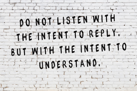 White brick wall with painted black motivational quote inscription.