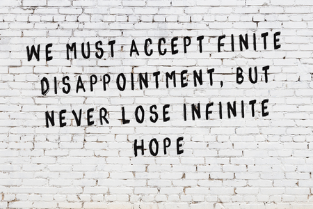 White brick wall with painted black motivational quote inscription.の写真素材