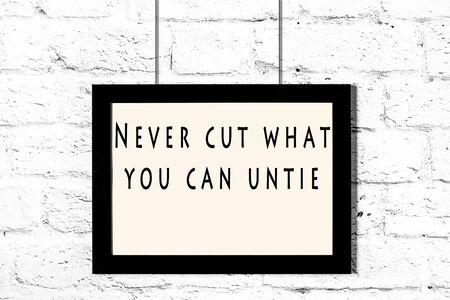 Black frame with wise quote hanging on a white brick wall.の写真素材