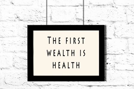Black frame with wise quote hanging on a white brick wall.の写真素材