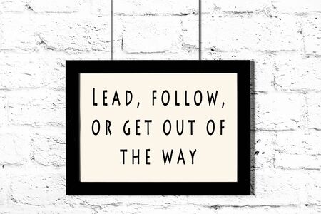 Black frame with wise quote hanging on a white brick wall.の写真素材