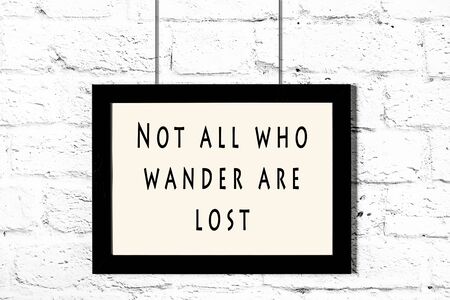 Black frame with wise quote hanging on a white brick wall.の写真素材