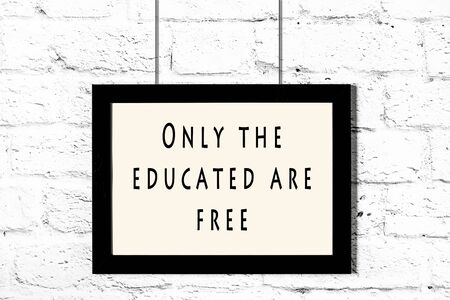 Black frame with wise quote hanging on a white brick wall.の写真素材