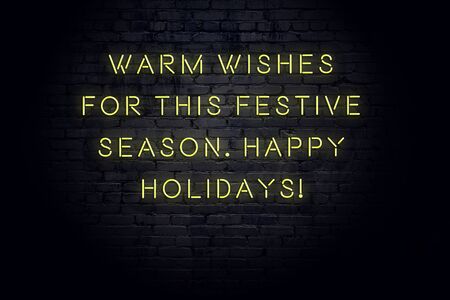 Neon inscription of christmas and new year greetings on brick wall.