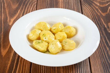 White plate full of boiled potatos on wooden tableの写真素材