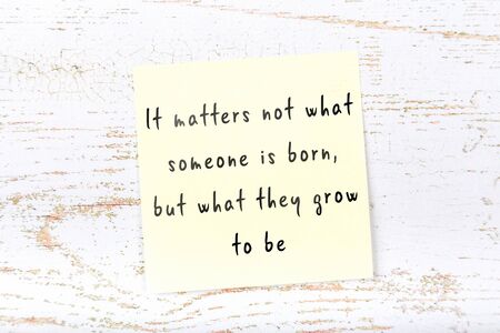 Yellow sticky note with handwritten motivational quotation on wooden wallの写真素材