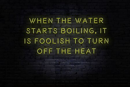 Wise quotation as light neon sign on brick wallの写真素材
