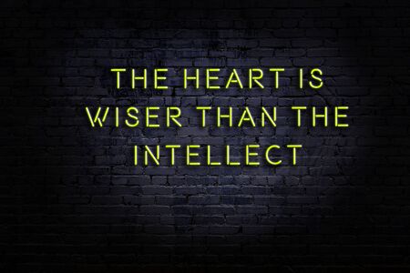 Wise quotation as light neon sign on brick wallの写真素材