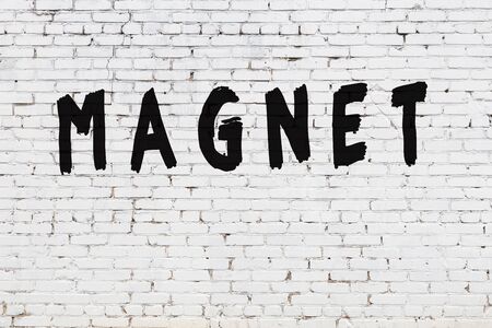 Word magnet written with black paint on white brick wall.の写真素材