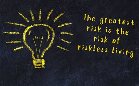 Wise quotation and a chalk drawing of a bulb on black chalkboardの写真素材