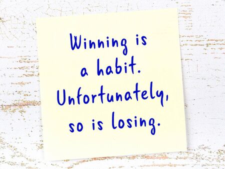Wise quotation handwritten on yellow sticky note hanging on wooden wall