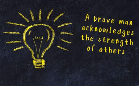 Wise quotation and a chalk drawing of a bulb on black chalkboardの写真素材