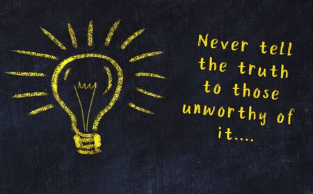 Wise quotation and a chalk drawing of a bulb on black chalkboardの写真素材