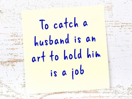 Yellow sticky note with handwritten motivational quotation on wooden wall