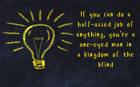 Wise quotation and a chalk drawing of a bulb on black chalkboardの写真素材