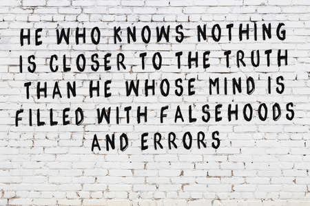 White brick wall with black painted inscription of sensible wise quote on itの写真素材