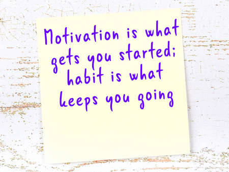 Yellow sticky note with smart quotation handwritten on it hanging on wooden wallの写真素材