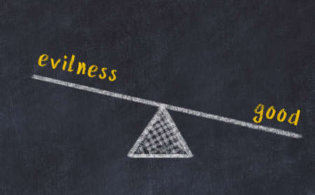 Balance between evilness and good. Chalkboard drawing on black chalkboardの写真素材