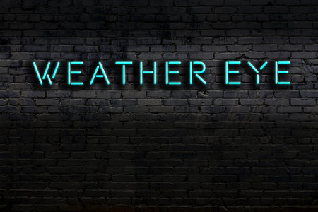 Neon sign with inscription weather eye against brick wall. Night viewの写真素材