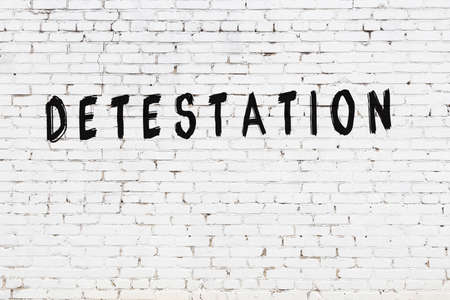 White brick wall with inscription detestation handwritten with black paintの写真素材
