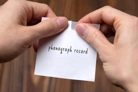 Canceling phonograph record. Hands tearing of a paper with handwritten inscription.の写真素材