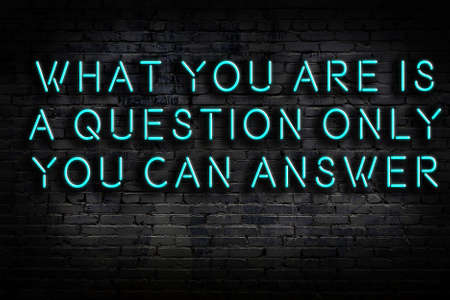 Wise quotation as light neon sign on brick wallの写真素材